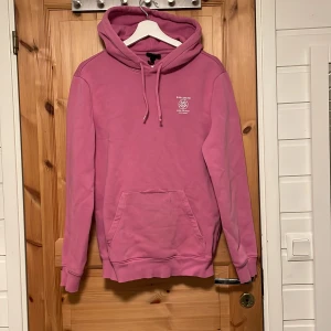 Rosa hoodie från H&M - Säljer en snygg rosa hoodie från H&M i storlek XS. Tröjan har en klassisk design med känguruficka och justerbar huva. Perfekt för en avslappnad stil. (Det finns ett hål i fickan på framsidan)
