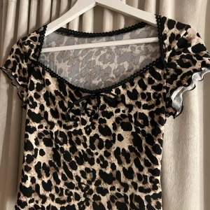 Leopardmönstrad topp med spetsdetaljer - Snygg leopardmönstrad topp med svarta spetsdetaljer och en liten rosett framtill. Supersöt sommartopp, skiv gärna om ni undrar nåt
