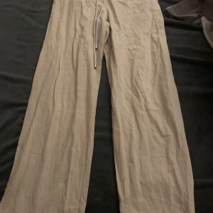 Beige linnebyxor från Shein - Snygga beige linnebyxor från Shein med en avslappnad passform. Byxorna har en dragsko i midjan för justerbar passform och är perfekta för en bekväm stil. Perfekta för varma dagar!