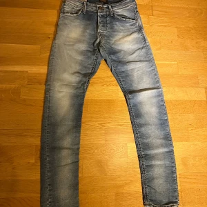 Blåa Jack&jones jeans - Snygga blå jeans från jack&jones med en cool slitningseffekt. De har en klassisk femficksdesign och en bekväm passform. Perfekta för en avslappnad stil.