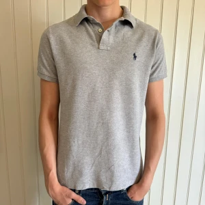 Ralph Lauren Piké - En riktigt fin Ralph Lauren pike i en snygg grå färg! Skick 9/10, skulle behövas strykas möjligtvis?😅Storlek M. Modellen är 183 och väger ca 70kg. Hör gärna av er vid eventuella frågor🤗