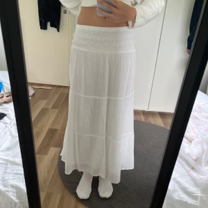 Vit långkjol  - Säljer en vit långkjol från Gina Tricot med smock i midjan och lätt, flowigt tyg. Kjolen har en luftig känsla och är perfekt för varma dagar. Enkel och stilren design som passar till många olika looks. Säljer den för att den har blivit för kort och den sitter jättebra. Pris går att diskuteras!