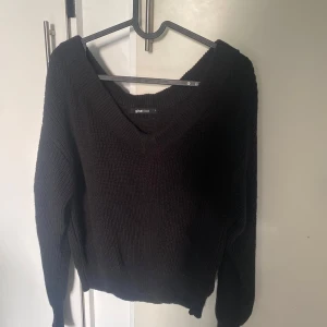 Svart stickad v-ringad tröja från Gina Tricot - Mysig svart stickad tröja från Gina Tricot med djup v-ringning. Tröjan har lång ärm och bred ribbad kant vid hals, ärmslut och nederkant. Perfekt för lager-på-lager och passar till det mesta.