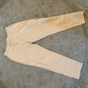 Beige mjukisbyxor från SHEIN - Säljer ett par beige mjukisbyxor från SHEIN i storlek M. Byxorna har resår i midjan med snörning och är tillverkade i ett mjukt material som passar perfekt för en avslappnad stil.