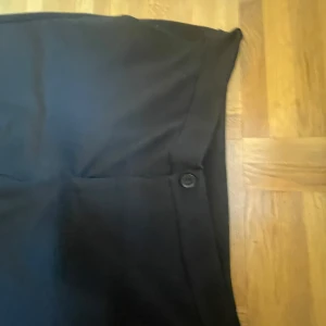 Svarta kostymbyxor från Lindex - Säljer ett par svarta kostymbyxor från Lindex i storlek S. Byxorna har raka, vida ben och stängs med knapp och dragkedja. Perfekta för en stilren och klassisk look. Ganska stora för att vara S