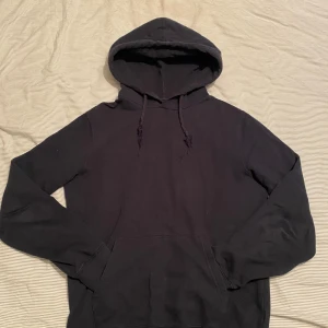 Vanlig Blå hoodie - En klassisk blå hoodie med huva och dragsko. Tröjan har långa ärmar och en stor magficka framtill. Perfekt för en avslappnad stil och enkel att matcha med det mesta.