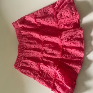 Rosa broderad kortkjol från FB Sister - Supersöt rosa kortkjol från New Yorker med broderade blommor och resår i midjan. Kjolen har volanger och är perfekt för dig som vill ha en lekfull och färgglad stil. Passar perfekt till sommaren!