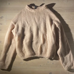 Beige stickad tröja från H&M - Mysig beige stickad tröja från H&M med hög hals och ribbade muddar. Perfekt för kyliga dagar och enkel att matcha med olika outfits.