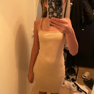 Beige  klänning med smala axelband - Jag säljer en beige tajt klänning, den är kort men passar för att den inte passade just mig. Den är från Amisu och är i storleken 34.