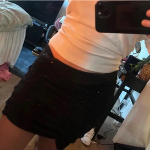 Svart klittrig kjol - Snygg svart kortkjol med glittrande detaljer. Perfekt för en kväll ute eller festliga tillfällen. Kjolen har en tight passform som framhäver figuren. Aldrig använd💕
