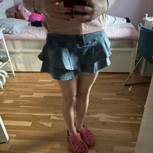 Jeanskjol med volang - Supersöt kort jeanskjol med volanger och inbyggda shorts. Midjemåttet tvärs över är ca 34 cm och längden på kjolen är ca 33 cm. Använd gärna köp nu 💗