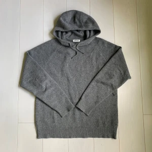 Soft Goat Kashmir Hoodie - Nyaste kollektionen av Soft goat! Mysig grå hoodie från Soft Goat i 100% kashmir. Tröjan har huva med dragsko och långa ärmar samt ribbade muddar vid ärmslut och nederkant. Perfekt för dig som gillar en klassisk och stilren look med extra komfort. Super bra skick, inga defekter, Nypris 3695kr