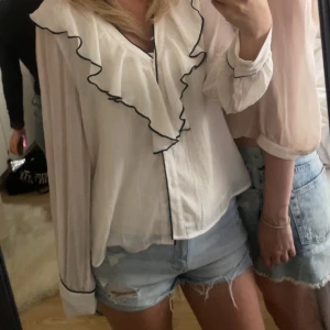 Vit blus från Zara - Säljer en vit blus med volangkant och svarta kontrastsömmar från Zara 🩷