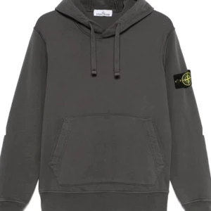 Grå hoodie från Stone Island - Snygg grå hoodie från Stone Island med klassisk känguruficka och justerbar huva. Den har en ikonisk logotyp på ärmen som ger en cool touch. Perfekt för en avslappnad stil. har ingen egen bild för tillfället men kan lösas snart. Den är i storlek L.   Tar även byten!