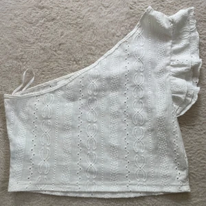 Vit one shoulder topp med volang - Säljer denna vita one shoulder topp då den inte kommit till användning! Den är endast testad och aldrig använd så den är i väldigt bra skick! 😊 Hör av dig om du vill ha fler bilder eller om du undrar något! 💓🤍