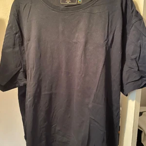 3 st Svarta t-shirtar från Dressmann - En klassisk svart t-shirt från Dressmann med rund halsringning. T-shirten är enkel och stilren, perfekt för en avslappnad look. Tillverkad i mjuk bomull och har normal passform med korta ärmar.