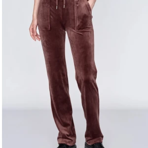 Bruna juciy byxor  med snörning - Mysiga bruna mjukisbyxor i mjukt material med raka ben och snörning i midjan. Byxorna har fickor fram och bak, samt dekorativa knappar på bakfickorna. Perfekta för en avslappnad stil. Inga hål, det finns även med matchade tröja bild kan skickas 