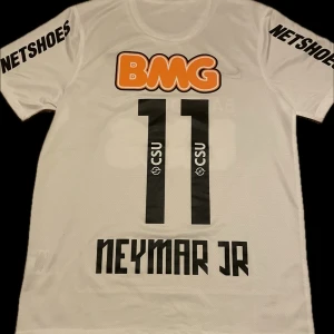 Vit Santos fotbollströja Neymar Jr - Säljer en vit Santos fotbollströja med Neymar Jr och nummer 11 på ryggen. Klubbmärket sitter på bröstet och materialet är lätt och andas. Sponsor och namn är tryckt, Kommer med tags och påse 