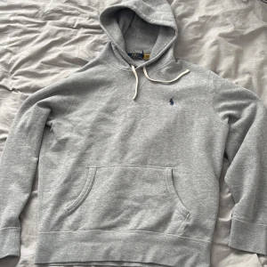 Polo Ralph Lauren grå hoodie - Säljer en grå hoodie från Polo Ralph Lauren med broderad blå logga på bröstet. Den är M men sitter som S. 
