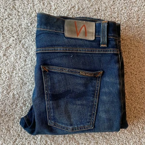 Mörkblå Nudie Jeans Lean Dean - Snygga mörkblå jeans från Nudie jeans. Modellen är Lean Dean. De är i bra skick och har tagits hand om väl. Storleken är W30 L32. Nypris på dessa ligger på 1600, mitt pris är 499 men pris går att diskutera vid snabb affär💸. Skriv vid minsta fundering 🤔 