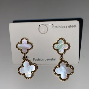  guld klöver örhängen! Lik van cleef INGÅR PLUPPAR - Säljer dem här super fina örhängena i Guld stainless steel! Vit i mitten och matchar med ett klöver halsband som jag säljer.
