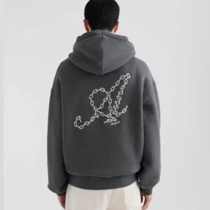 Hoodie från Axel Arigato - Säljer en mörkgrå hoodie från Axel arigato  med en stor kedje-design i vitt på ryggen och liten logga framtill. Hoodien har en klassisk passform med känguruficka och ribbade muddar. Perfekt för en avslappnad stil. Köpt i Göteborg i butik. 
