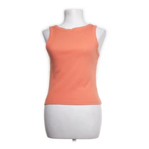 Persikofärgad ribbad linnetopp - En enkel och snygg persikofärgad linnetopp med ribbad struktur. Toppen är ärmlös och har rund halsringning, perfekt för varma dagar. Passformen är normal och materialet känns mjukt mot huden.