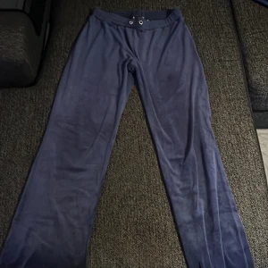 Blå velour mjukisdress med hoodie - Mysig blå mjukisdress i velour med matchande byxor och hoodie. Hoodien har dragkedja, fickor och snörning vid halsen. Byxorna har resår i midjan och snörning. Perfekt för chill dagar eller när du vill vara extra bekväm.