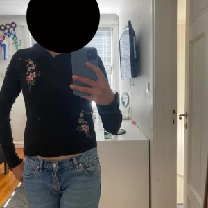 Svart hoodie med blommor FB Sister XS - Svart hoodie från FB Sister i storlek XS med broderade blommor i rosa, rött och grönt. Ena ärmen är lite sliten (se bild) annars är den hel. Tunnt material. 