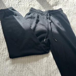 Svarta mjukisbyxor med snörning, S - Svarta mjukisbyxor i storlek S med elastisk midja och snörning. Byxorna har en klassisk loose passform och är tillverkade i mjukt bomullsmaterial, perfekta för chill dagar eller när du vill vara bekväm. Enkla att matcha med hoodies eller t-shirts.