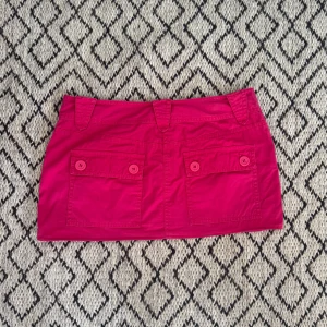 Minikjol från hm - Supersnygg  rosa kjol från H&M med två stora fickor med knappar bak. Cool färg. Sytt upp den. 