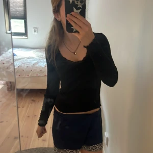 Svart långärmad topp med spets - Supersnygg svart långärmad topp med v-ringning och spetsdetaljer vid halsen. 