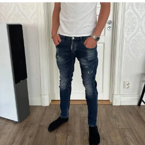 Mörkblå skinny jeans med slitningar - Snygga mörkblå skinny jeans från Alessandro Zav med slitna detaljer och färgstänk. Jeansen har klassisk femficksdesign, låg midja och smal passform. Perfekta för dig som gillar en trendig och avslappnad look.
