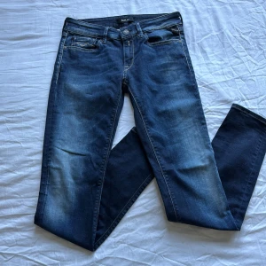Replay LUZ jeans blå,, 27/30 - Snygga blå jeans från Replay, modell LUZ, med klassisk femficksdesign och coola broderade bakfickor. Jeansen har en midwaist passform och raka ben. Tillverkade i stretchig bomullsdenim för skön känsla och stilren look.