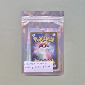 Japanska Pokémon Mystery Pack 5 Kort - Upptäck spänningen med ett japanskt Pokémon mystery pack! Innehåller 5 samlarkort i en glittrig förpackning, perfekt för dig som älskar Pokémon och vill överraska dig själv med nya kort. Passar både samlare och fans av Pokémonvärlden. Får även med sig random stickers. Vad gör kort finns i paket R, RR, AR