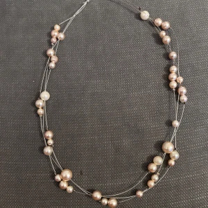 Flertrådigt halsband med pärlor - Snyggt halsband med flera tunna silverfärgade trådar och oregelbundet placerade pärlor i olika storlekar. Pärlorna är vita och ger ett elegant och trendigt intryck. Perfekt för dig som gillar att sticka ut med accessoarer som känns både moderna och klassiska.