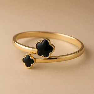 Guldigt armband med svarta blommor - Snyggt guldigt armband med två svarta blommor i klöverformade detaljer. Perfekt accessoar för att lyfta din outfit med en cool och trendig touch. Armbandet har en stilren och modern design som passar dig som gillar att sticka ut.