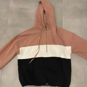 Colorblock hoodie från Zara - Snygg hoodie från Zara med colorblock-design i beige, vitt och svart. Tröjan har huva med snörning, half zip-dragkedja och långa ärmar. Perfekt för chill dagar och streetstyle. Materialet känns mjukt och skönt mot huden.