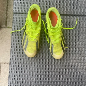 Neongula adidas fotbollsskor crazyfast - Obs: kolla bilder för defekter på skorna.           Säljer ett par neongula adidas fotbollsskor med svarta detaljer och orange sula. Skorna har snörning och är tillverkade i syntetmaterial. Perfekta för dig som vill sticka ut på planen. Perfekt för någon som spelar fotboll men inte vill spendera mycket pengar
