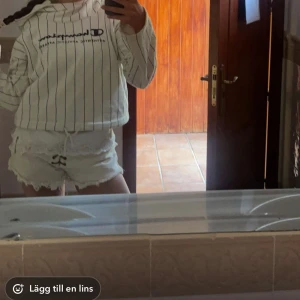 Vit randig hoodie från Champion - Säljer en vit hoodie från Champion med svarta tunna ränder och stor logga framtill. Tröjan har huva, långa ärmar och en relaxed passform. Perfekt för dig som gillar sportig och chill stil.