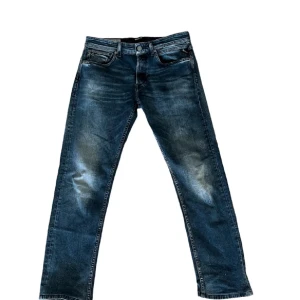 Replay Grover jeans blå herr - Snygga Replay Grover jeans i klassisk blå tvätt med slitningar och raka ben. Jeansen har fem fickor, normal passform och är tillverkade i mjukt bomullsjeansmaterial. Storlek 32. Super fint skick.