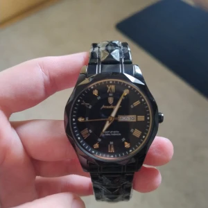 Svart klocka med guldiga detaljer - Stilren svart klocka från Pordora med guldiga visare och romerska siffror. Den glänser mycket och lockar fram brudarna 👀 men den är inte min stil