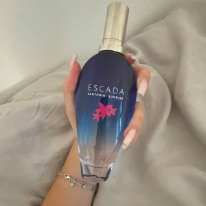 Escada Santorini Sunrise parfym 100ml - Fräsch parfym från Escada, Santorini Sunrise, i en snygg blå glasflaska med silverfärgad spraykork och rosa blomdetalj. Doften är inspirerad av Medelhavet och sommarvibbar. Oanvänd!💗💗