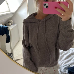 Beige stickad hoodie med huva - Mysig beige stickad hoodie med huva och snörning. Tröjan har en relaxed passform och långa ärmar med ribbade muddar. 