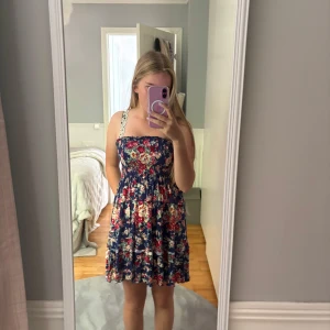 Blommig klänning  - Supersöt klänning med blommigt mönster. Det går att sätta fast axelband.