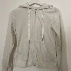 Vit hoodie med dragkedja från Gina Tricot - Säljer en vit hoodie från Gina Tricot i storlek XXS. Tröjan har mjukt material, huva med breda satinband och praktisk dragkedja framtill. Två fickor på magen och långärmad modell. Perfekt för chill dagar och enkel att matcha med jeans eller leggings.