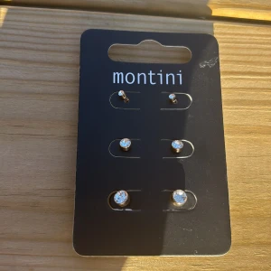 Guldiga örhängen med strass från Montini - Säljer ett set med sex guldiga örhängen från Montini, alla med glittrande vita strasstenar i olika storlekar. Perfekt för att mixa och matcha flera hål i öronen. 