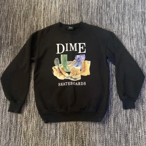 Svart sweatshirt från Dime Skateboards - Svart sweatshirt med skön vintage känsla från Dime Skateboards i storlek S. Framsidan har ett stort tryck med boots. Tröjan har rund hals, ribbade muddar och är långärmad. Tveka inte med att höra av dig om du har ett prisförslag eller annan fundering!
