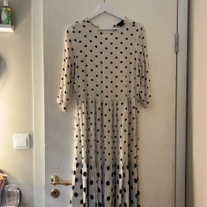 Prickig långklänning  - Säljer en beige långklänning med svarta prickar och trekvartsärm.  I storlek xs-s