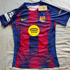 FC Barcelona Lamine Yamal matchtröja Nike S - Barça matchtröja med Lamine Yamal 10-tryck, Nike Dri-FIT ADV. Klassiska blå och röda ränder, gula detaljer och klubbmärke på bröstet. Spotify-logga framtill, UNHCR-tryck bak. Kortärmad och tillverkad i tekniskt funktionsmaterial.